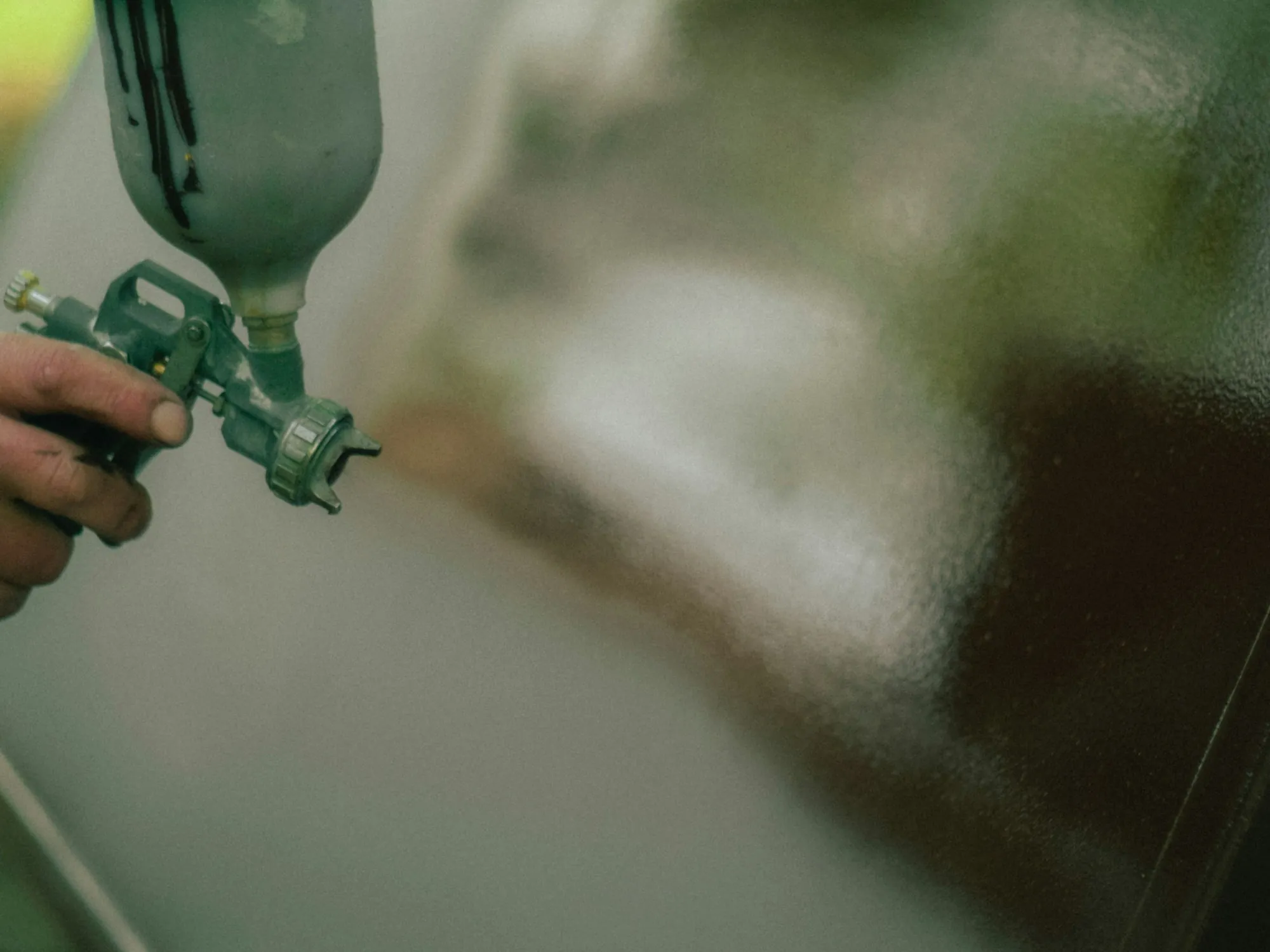 Close-up of a hand holding a green spray gun